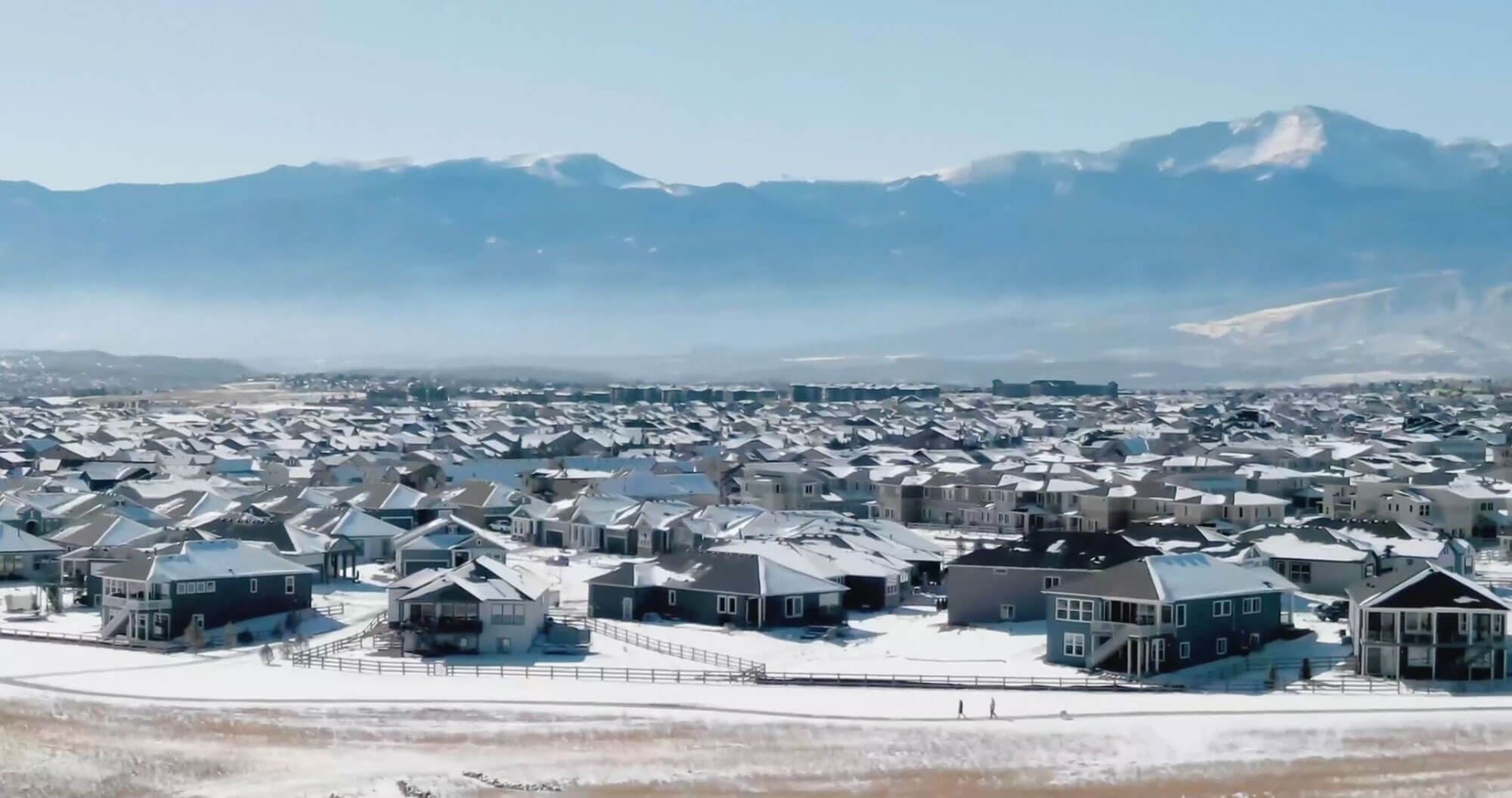 A view of a snowy master planned community and Colorado mountains